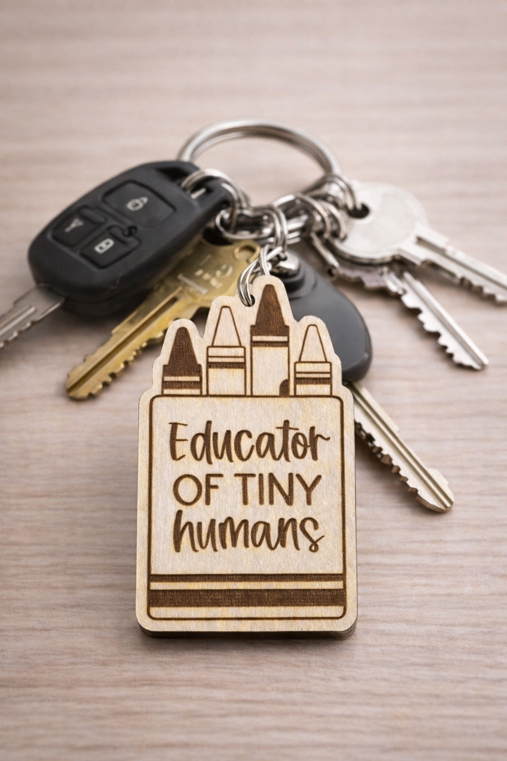 Keychain with 'Educator of Tiny Humans' text on a wooden tag, attached to keys.