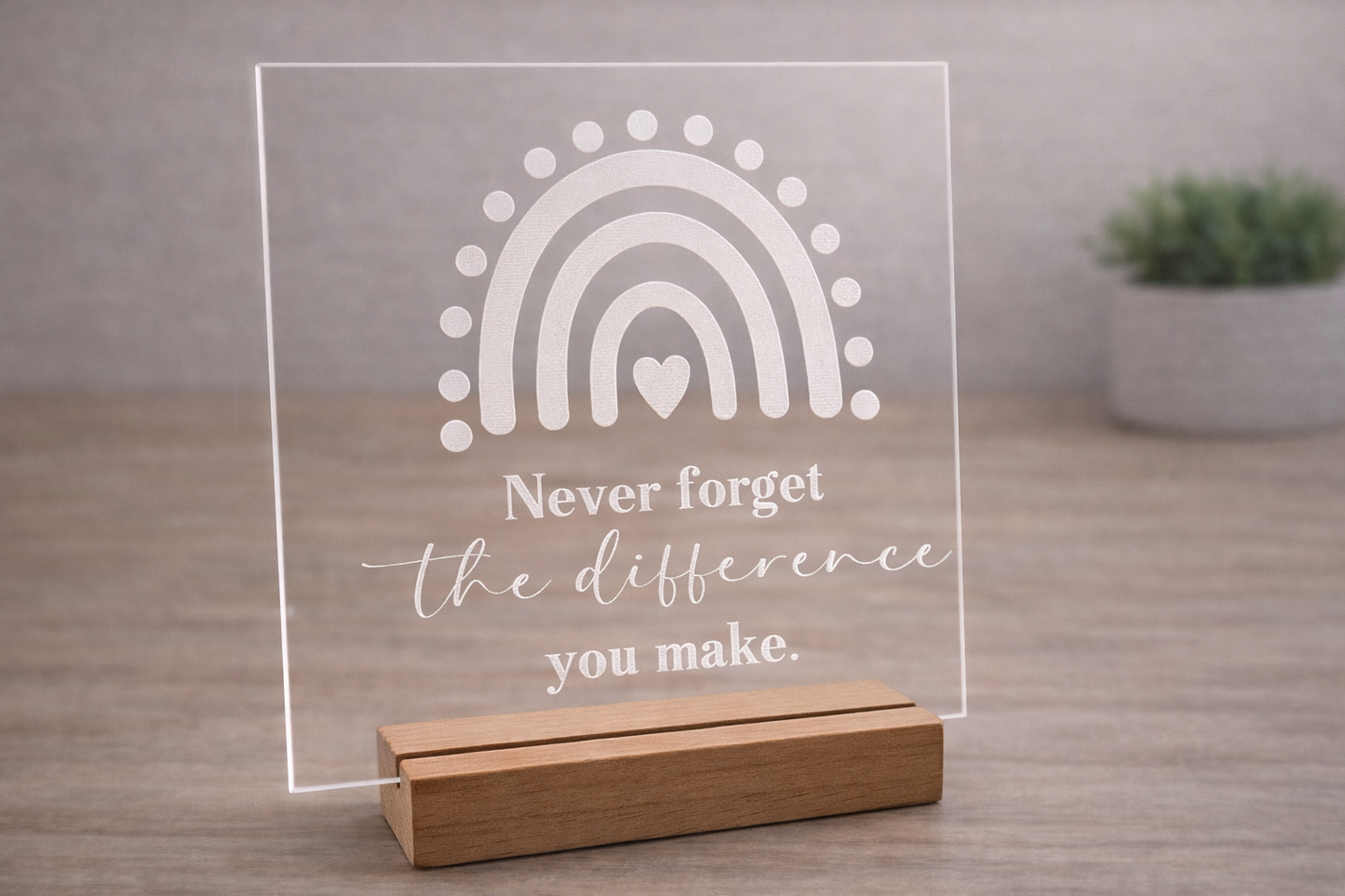 Acrylic plaque with rainbow design and motivational quote on a wooden stand.