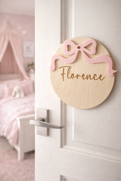 Decorative door sign with a pink bow and 'Florence' text in a bedroom setting.