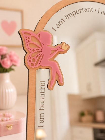 Decorative mirror with a pink fairy design and motivational phrases.